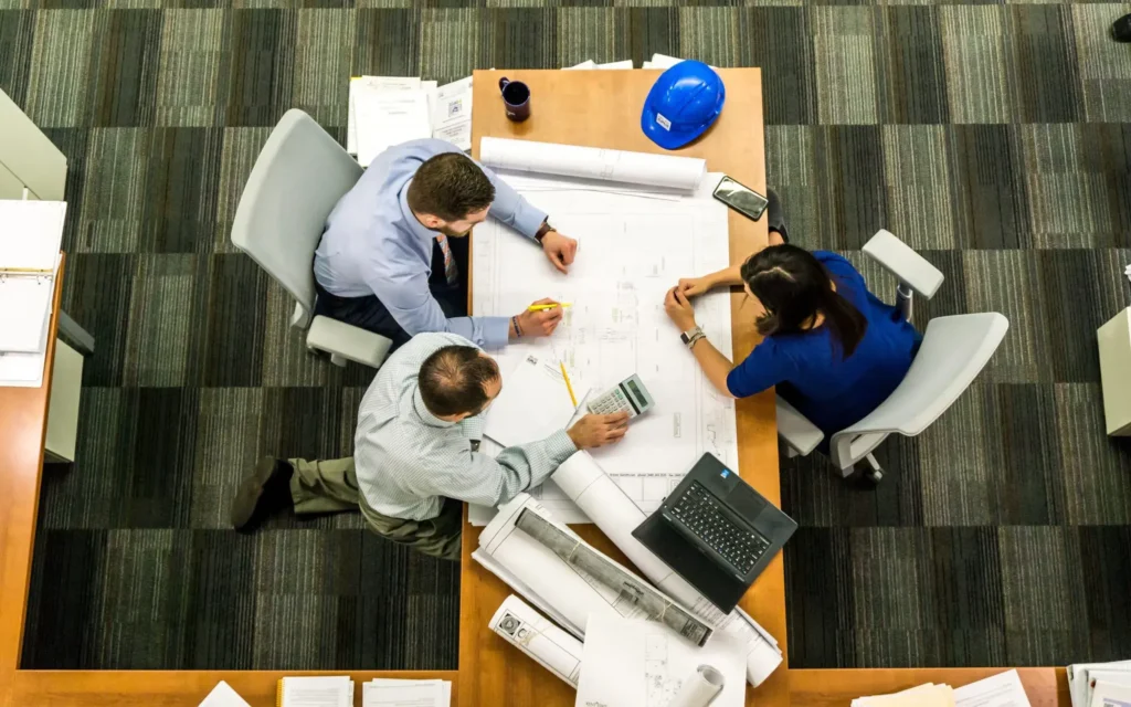 Reunión de arquitectos e ingenieros para la administración de obra y revisión de planos.