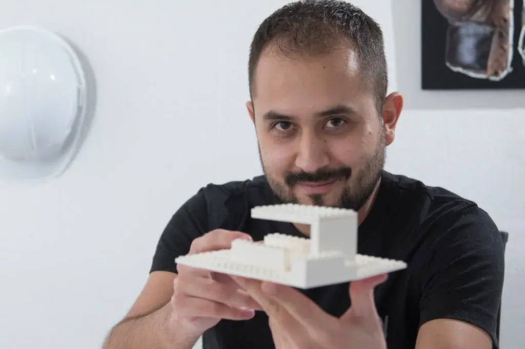 Fotografía de Luis sosteniendo una maqueta a escala de diseño arquitectónico conceptual.