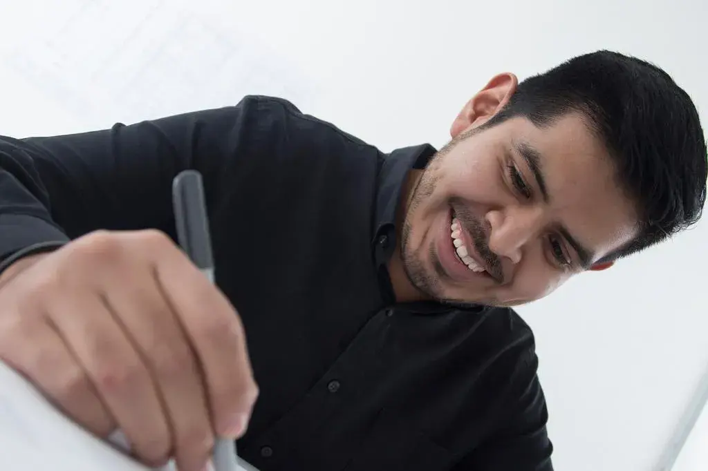 Retrato profesional de Misael, miembro del equipo de InOut Arquitectura, sonriendo y dibujando.