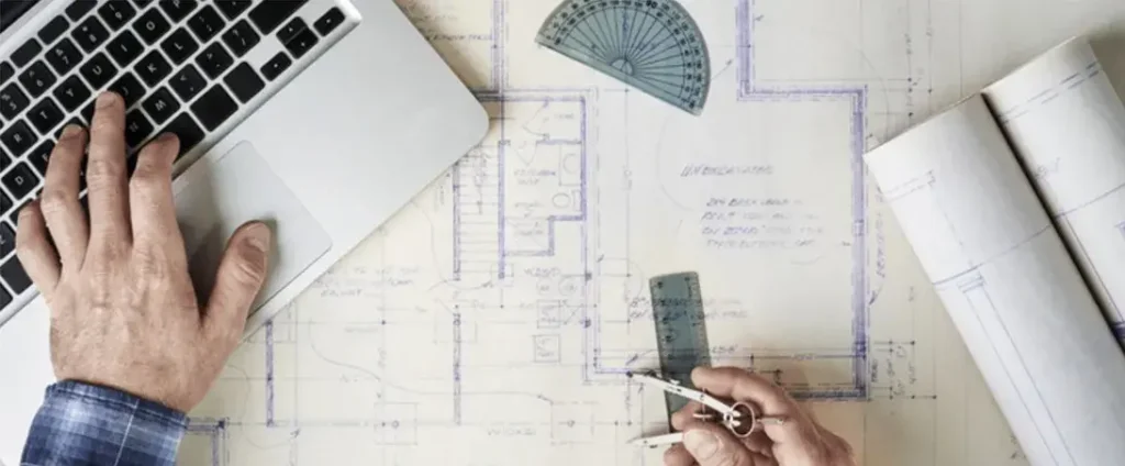 Boceto técnico y planos arquitectónicos con herramientas de medición sobre mesa de trabajo.