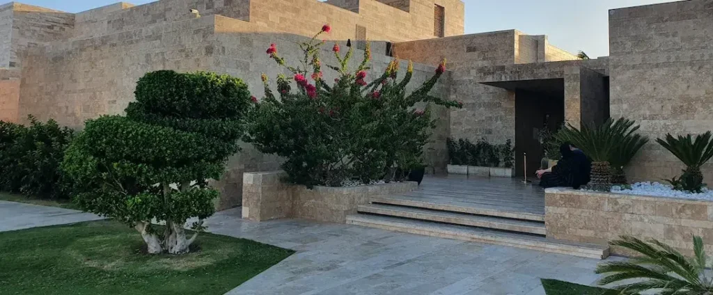 Fachada exterior de proyecto residencial moderno con vegetación y acabados en piedra.