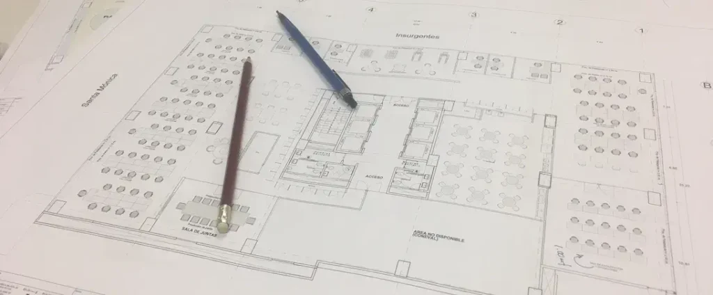 Plano arquitectónico impreso con pluma sobre escritorio de diseño de interiores.